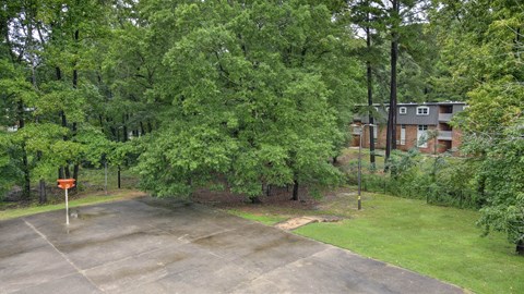 A parking lot surrounded by trees and a building in the background.