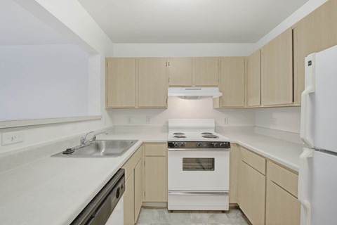 A kitchen with a white stove top oven and white cabinets.