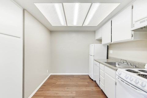 A kitchen with white appliances and wooden floors.