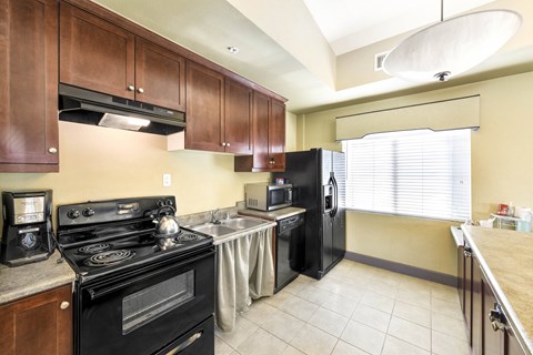 A kitchen with a black stove top oven and black refrigerator.