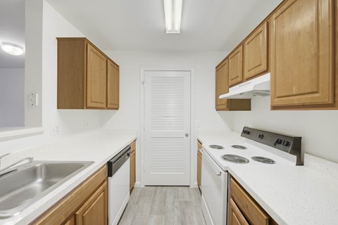 A kitchen with wooden cabinets and a white stove top oven.