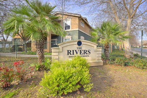 A sign that says "The Rivers" stands in front of a building.