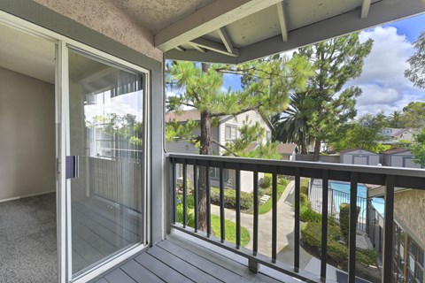 A balcony with a glass door leading to a pool area.