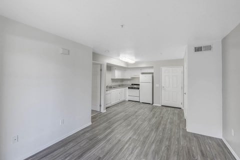 A kitchen with white cabinets and a countertop is visible from the living room.