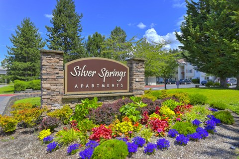 A sign for Silver Springs Apartments is surrounded by flowers.