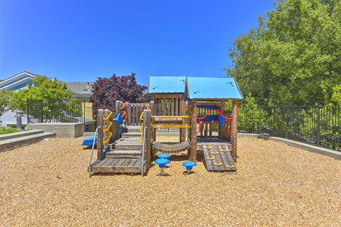 A playground with a blue roof and wooden slides.
