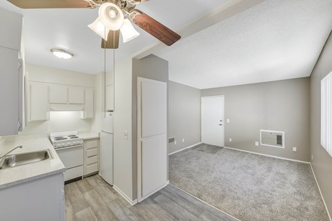 A kitchen with a sink, stove, and refrigerator with a fan in the ceiling.