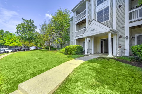 Apartment building exterior with landscaped walkway at Acclaim at Ashburn Apartments, Virginia, 20147