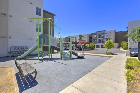 Playground area with green equipment and seating at Anton Arcade Apartments, Sacramento, 95825