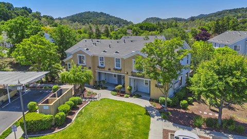 A house with a green lawn and trees in the background.