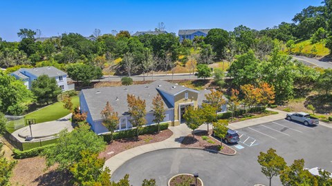 A parking lot is surrounded by trees and a building.
