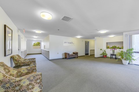 Bright hallway with lounge seating and plants at Hudson Gardens Apartments, Pasadena, CA