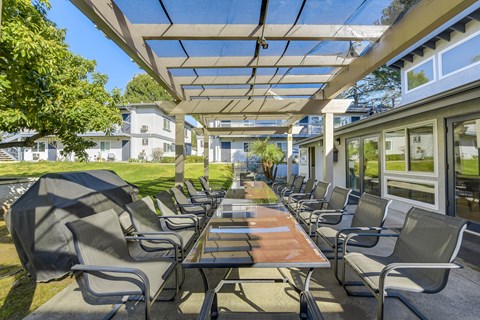 A patio with a table and chairs under a roof.