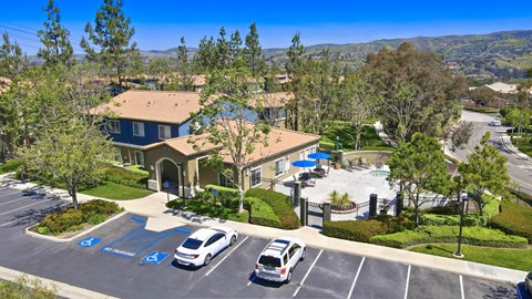 A parking lot with a building and a pool in the background.