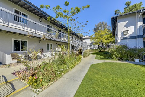 Courtyard walkway with lush garden beds and lawn at Heritage Park Apartments, Duarte, 91010