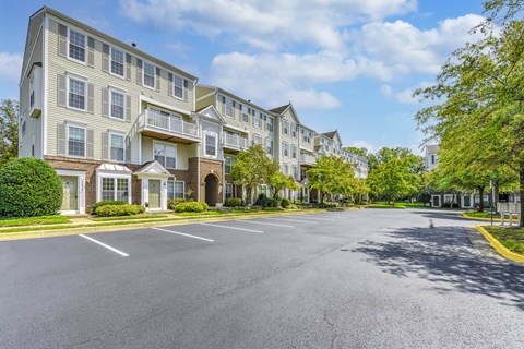 A sunny day at a residential complex with apartment buildings and a parking lot at Acclaim at Sterling, 20164