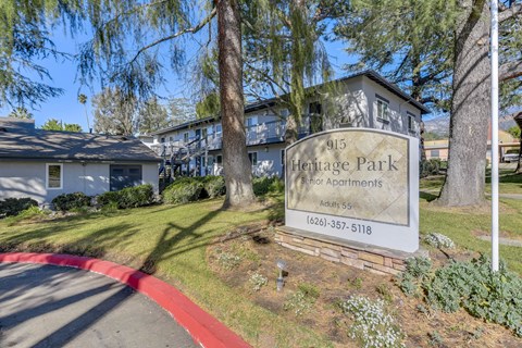 A sign for Heritage Park Apartments is in front of a building.