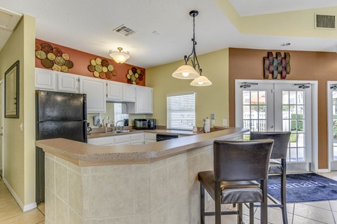 A kitchen with a black refrigerator and a bar area.