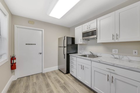 A kitchen with white cabinets and a black fridge.