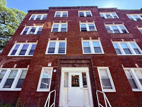 Red brick building with white doors at Logo Apartments, Roxbury, MA