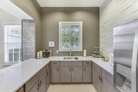 A kitchen with a stainless steel refrigerator and wooden cabinets.