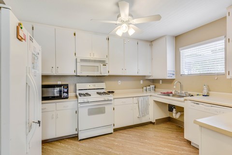 White kitchen with gas range and ceiling fan at Sutter Terrace Apartments, Roseville, California