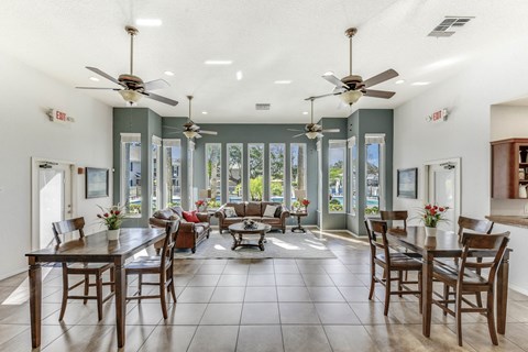 A dining room with a table surrounded by chairs and a ceiling fan.