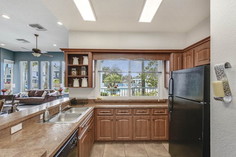 A kitchen with a black refrigerator and wooden cabinets.