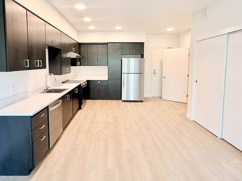A kitchen with black cabinets and a white refrigerator.