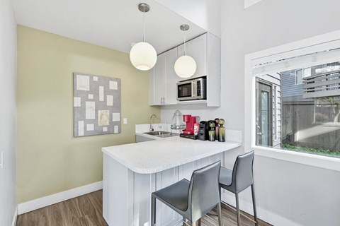 A kitchen with a white counter and grey chairs.