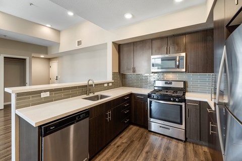 A modern kitchen with dark wood cabinets and stainless steel appliances.