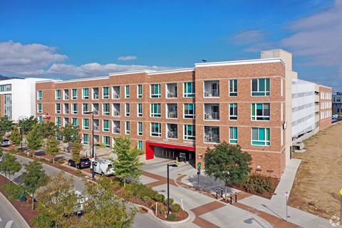 A large red brick building with a red awning sits in front of a parking lot.