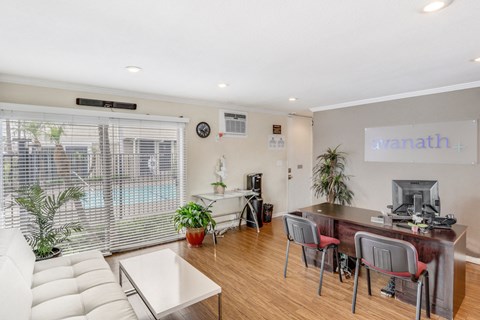 A living room with a white couch and a desk with a computer on it.