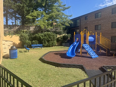 A playground with a blue slide and yellow fence.