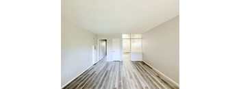 A long, empty hallway with white doors and wood flooring.
