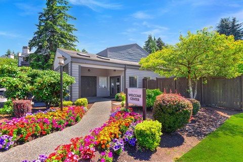 Welcome center entrance with colorful flower beds at Latitude Apartments, Everett, 98204