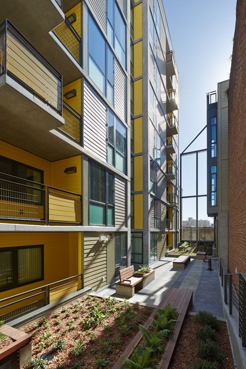 A modern building with a balcony and a garden in front.