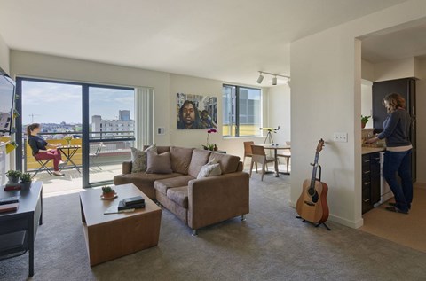 A woman is standing in a living room with a guitar leaning against the wall.