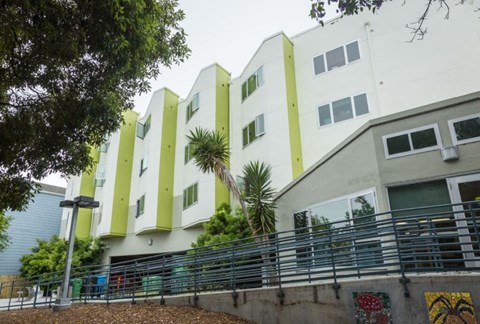 A white and green building with a balcony and a wall with graffiti.
