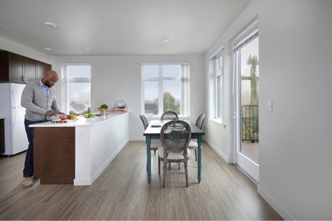 A man is preparing food in a modern kitchen with a dining table and chairs.