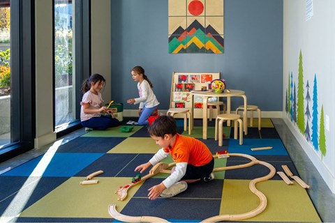 Children playing with a toy train in a colorful room.