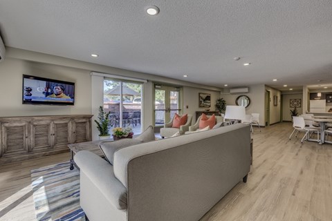 A modern living room with a large couch and a television mounted on the wall.