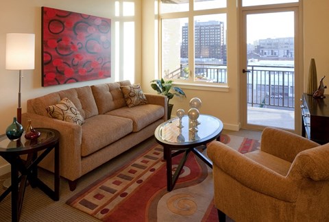 A living room with a couch, a chair, a table, and a painting on the wall.