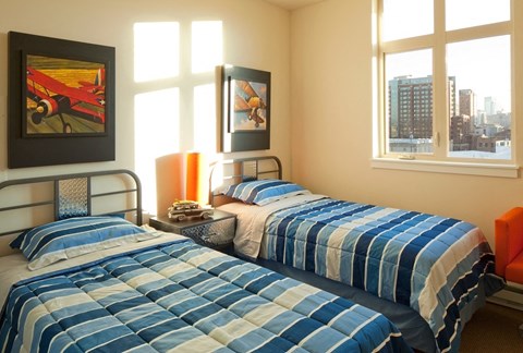 A bedroom with two beds and a window overlooking a cityscape.