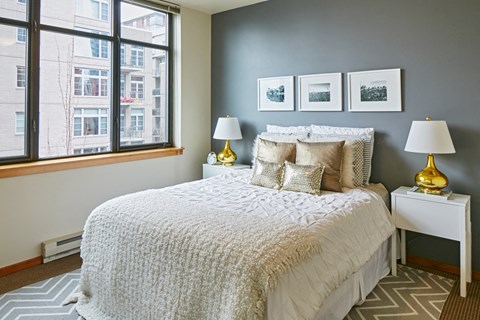 A bedroom with a large bed and a window overlooking a city.