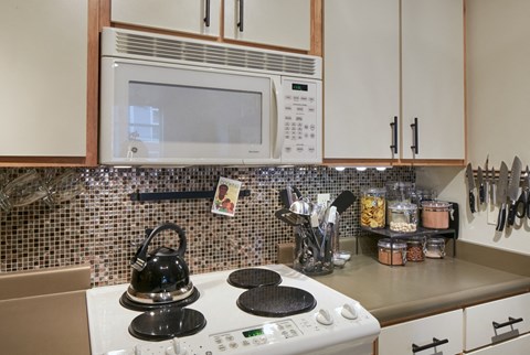 A kitchen with a white stove top and a microwave above it.