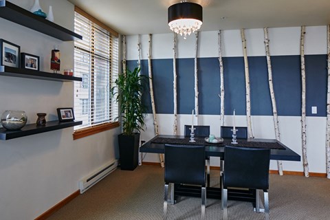 A dining room with a black table and chairs.