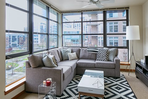 A living room with a grey couch and a coffee table in front of a large window.