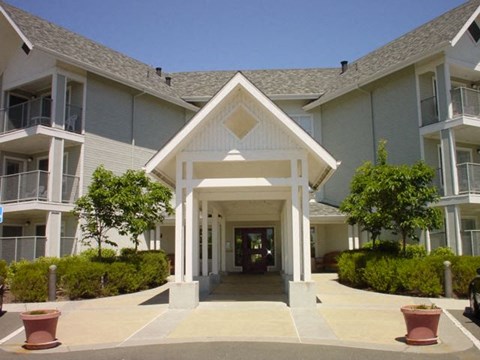 A white building with a triangular roof and a covered walkway.