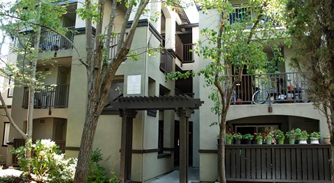 A building with a balcony and a tree in front of it.